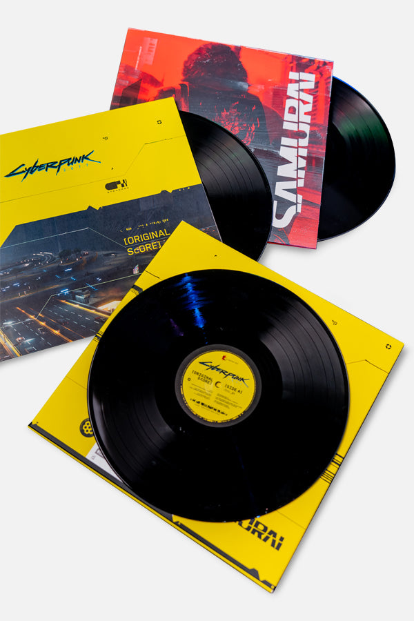3 LP Set of the Cyberpunk 2077 soundtrack with unique cover artworks. LP1: Circuit board design LP peeks out, LP2: Johnny Silverhand's back LP partially visible, LP3: Night City streets LP lying on its cover in iconic yellow and black colors